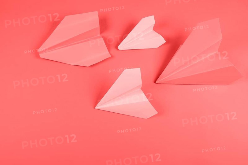 Coral pink paper airplane colored background