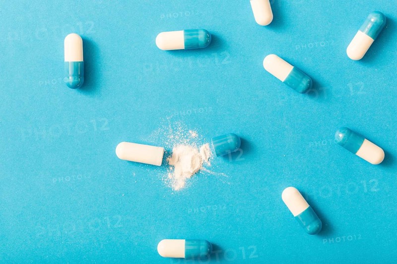 Split open capsule with white powder blue background