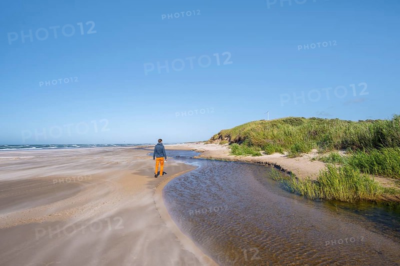 Tourist on sandy beach by the sea with overgrown dunes