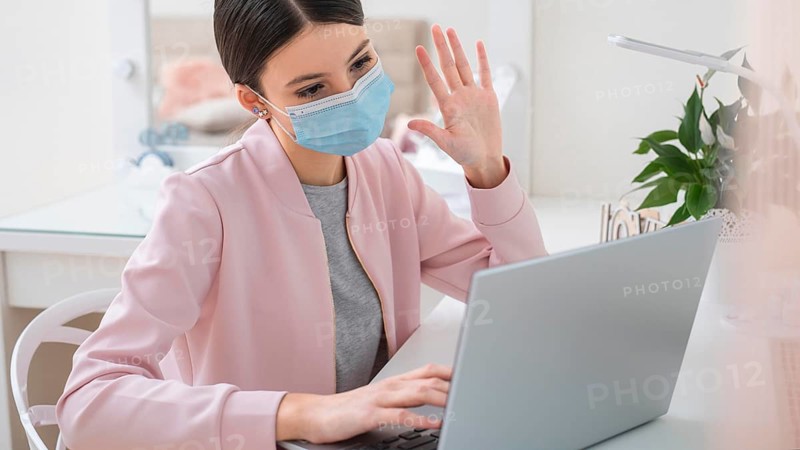 Young business woman working from home wearing mask