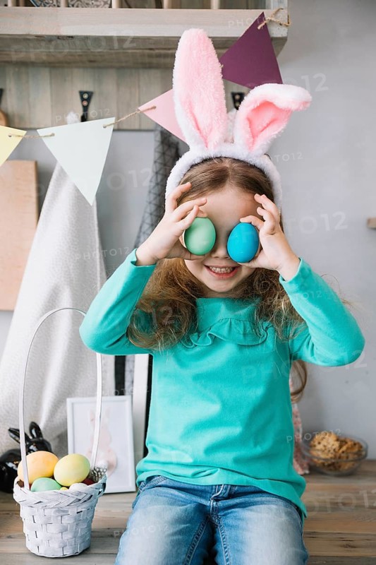 Cute girl bunny ears holding colored eggs eyes