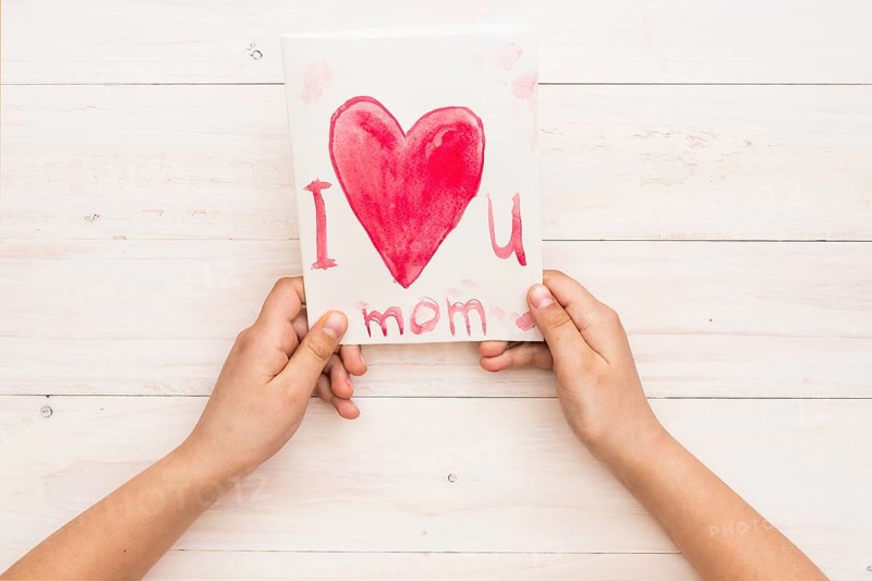 Person holding paper with i love you mom inscription