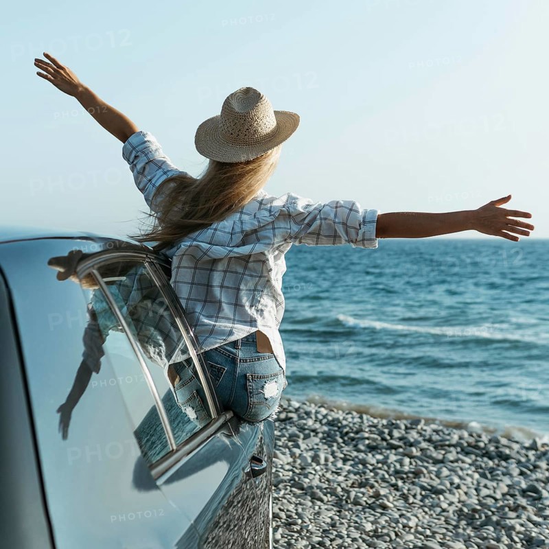 Blonde woman with hat standing out car window
