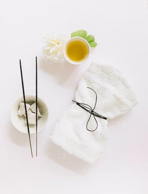 Top view incense stick pumice stone flower gingko leaf oil tied napkin white background