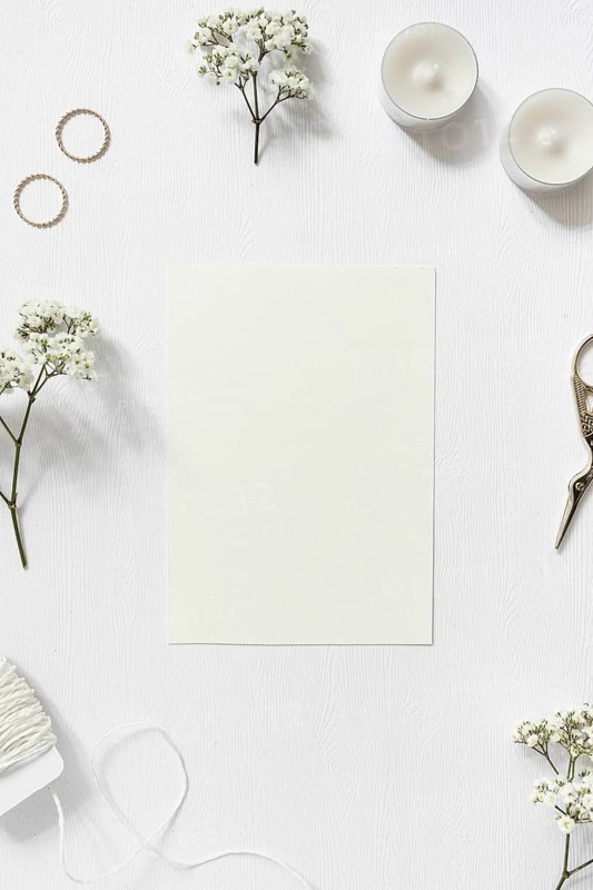 Blank card surrounded with gypsophila wedding rings string scissor white background