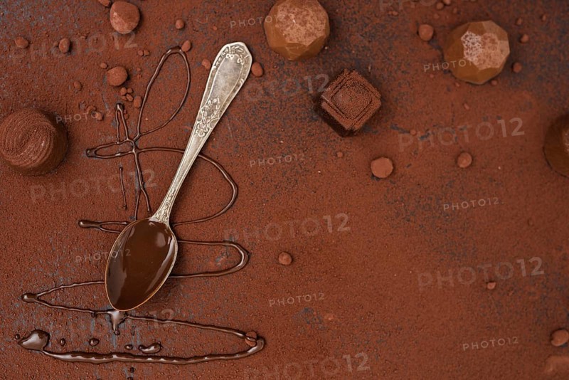 Spoon with chocolate syrup truffles cocoa powder
