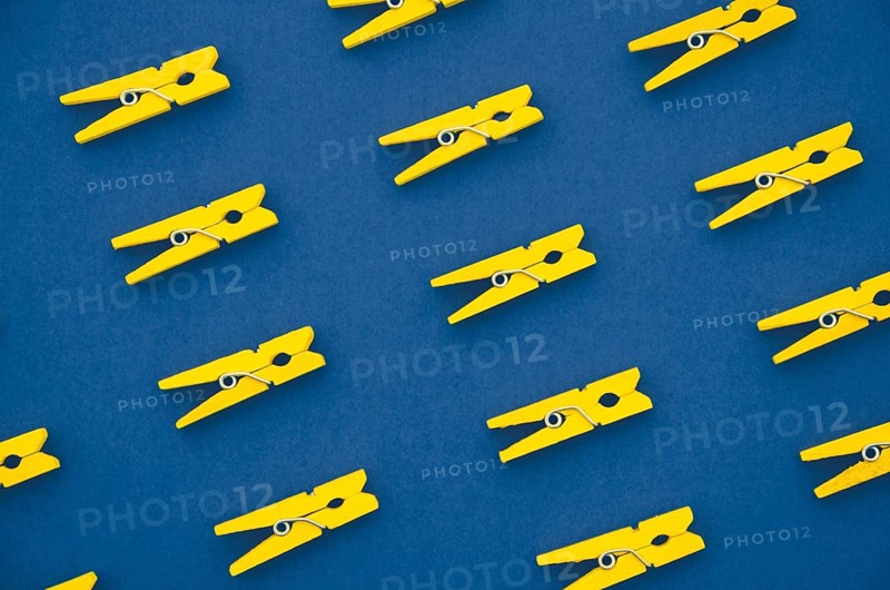 Flat lay yellow clothes pins blue background