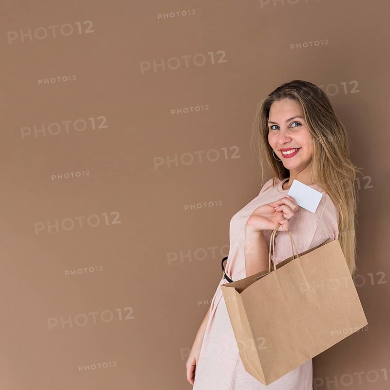 Happy woman standing with shopping bag credit card
