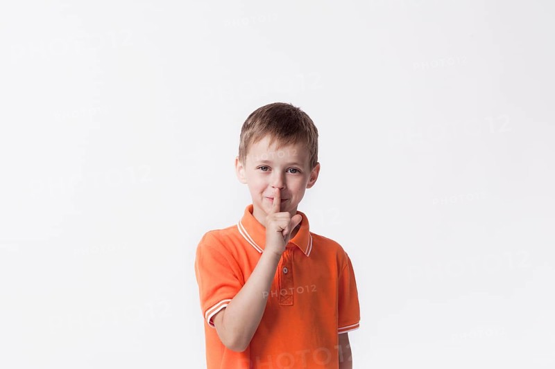 Smiling boy with finger lips making silent gesture