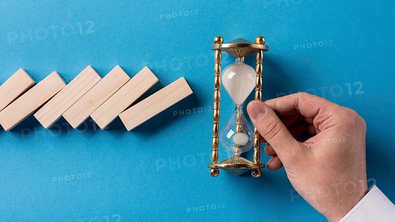 Top view domino pieces with businessman holding hourglass
