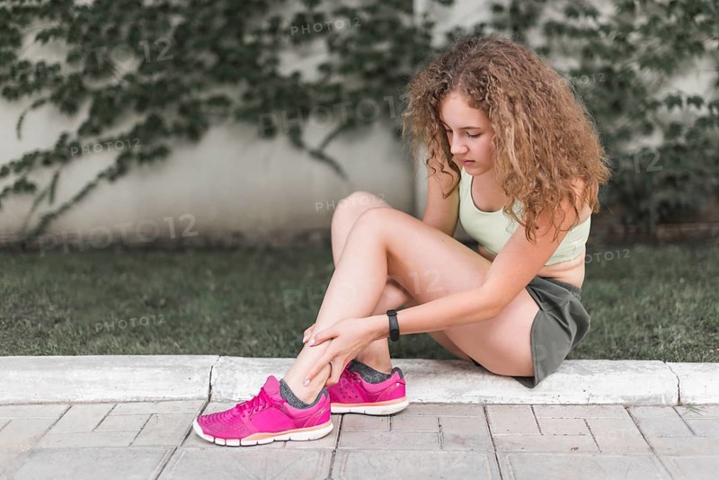 Woman sitting park looking injured ankle