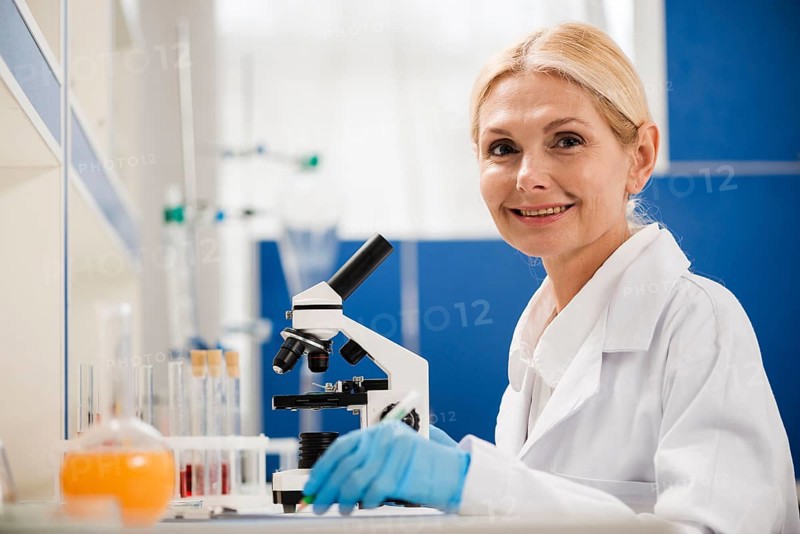 Side view female scientist posing lab with microscope surgical gloves