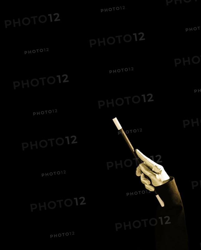 Magician s hand holding magic wand against black background