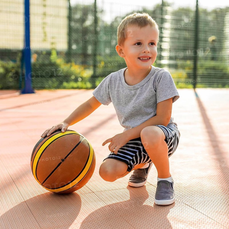 Happy boy playing basketball outdoors