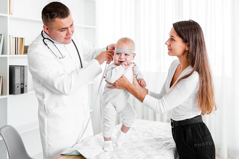Mother holding baby while doctor looking it