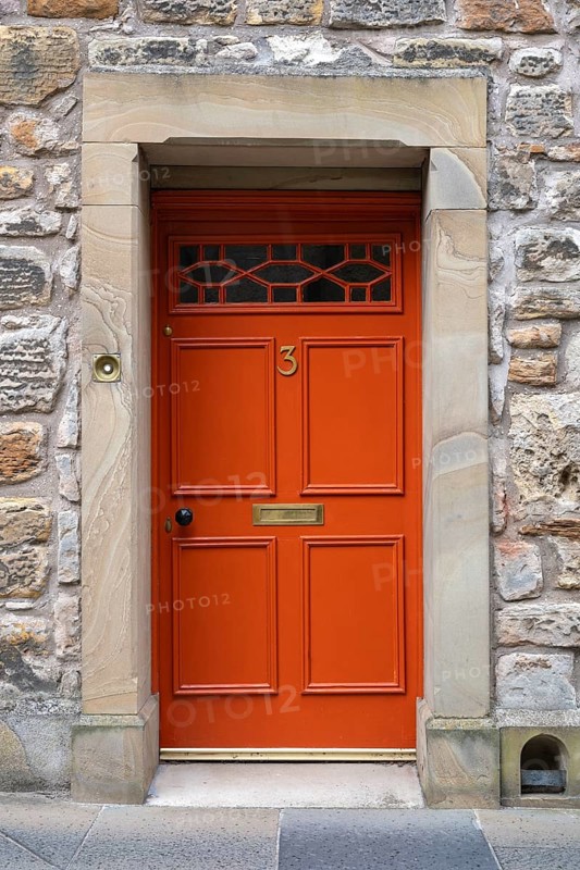 Red front door on an old stone house
