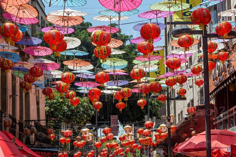 Red paper Chinese lanterns and umbrellas hanging above the street in Chinatown