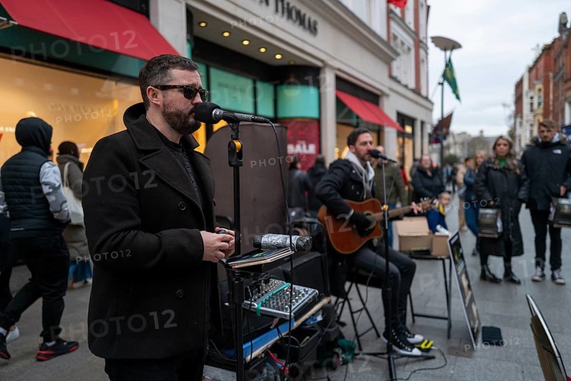 Andrew Kavanagh of Irish group Keywest singing in Grafton street with Andrew Glover in the back ground. Dublin