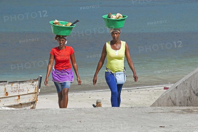 Two Creole women carrying plastic tubs with coconuts out of the harbour of Tarrafal on the island Santiago