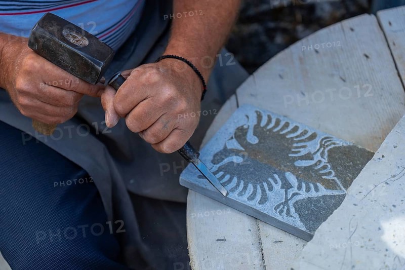 Albanian sculptor chopping making the country's coat of arms in the stone