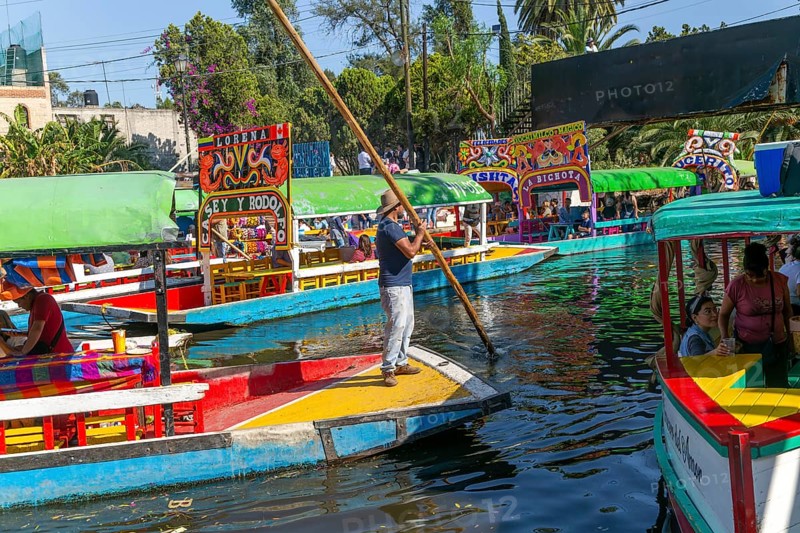 Popular tourist attraction people boating on colourful barges on canal at Xochimiloco