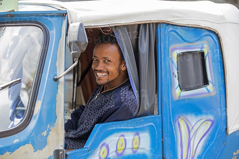 Black taxi driver smiling in tuk-tuk