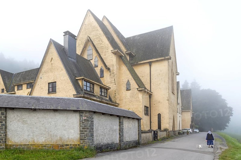 Cistercian nun walking her dog in front of the Abbaye Notre-Dame de Clairefontaine