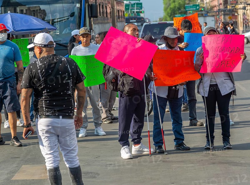 Blind visually impaired protestors holding placards block traffic on busy city centre road