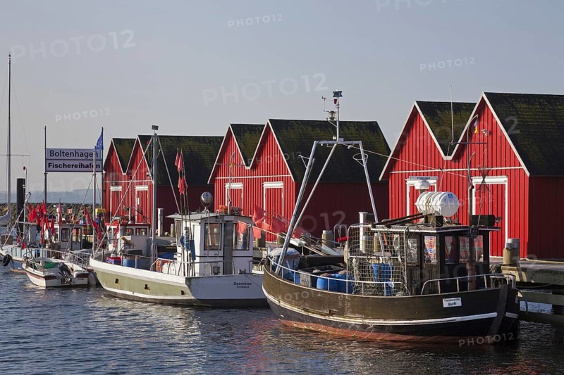 Fishing boats moored in front of red wooden huts in the harbour of Boltenhagen along the Baltic Sea