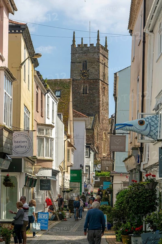 Shops in historic buildings along alleyway with tower of church of St Saviour