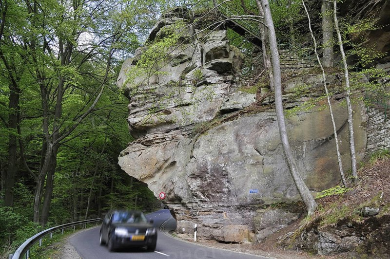 Car driving under the sandstone rock formation Predigtstuhl in Berdorf