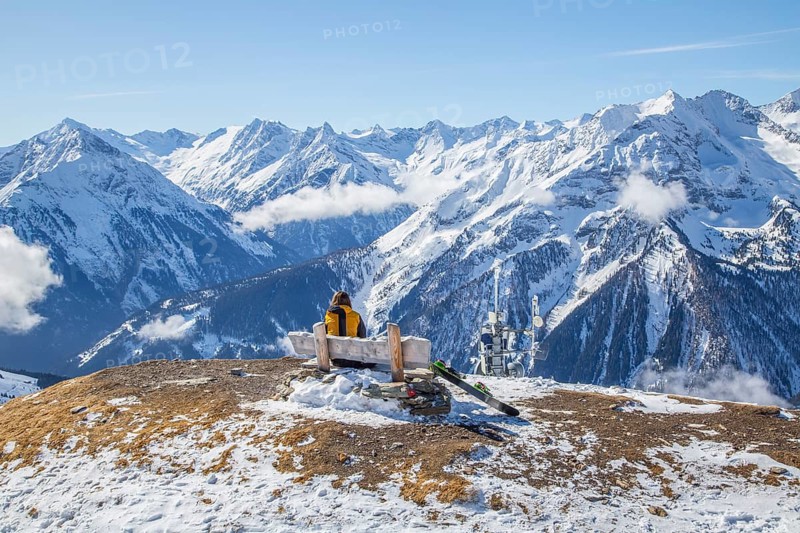 Skier sits on a bench and looks at the alpine chain