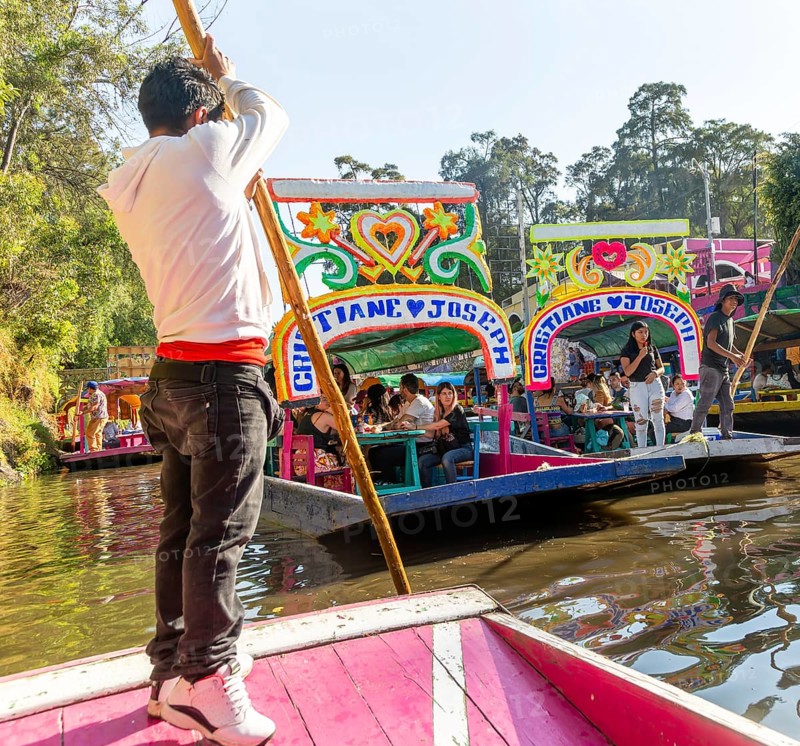 Popular tourist attraction people boating on colourful barges on canal at Xochimiloco