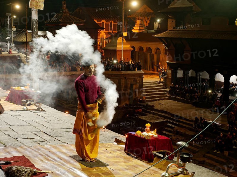 Hindu priest performing a ritual with smoke at night in front of the Pashupatinath temple
