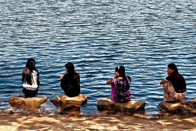 Women squatting on stones by the lake