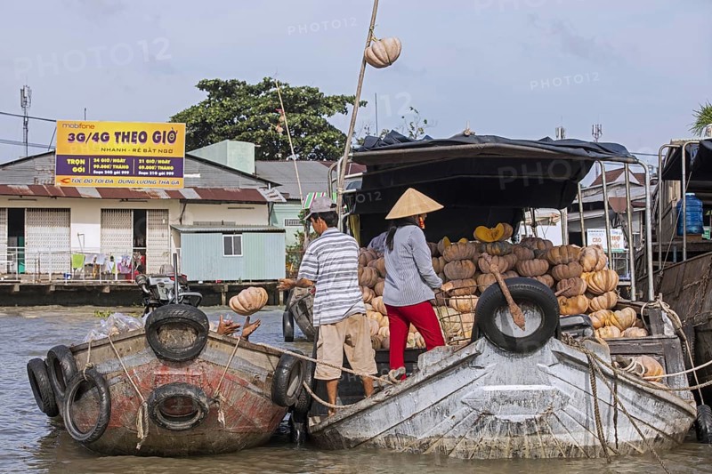 Vietnamese farmers selling pumpkins from traditional wooden boat at the floating market of the city Can Tho in the Mekong Delta