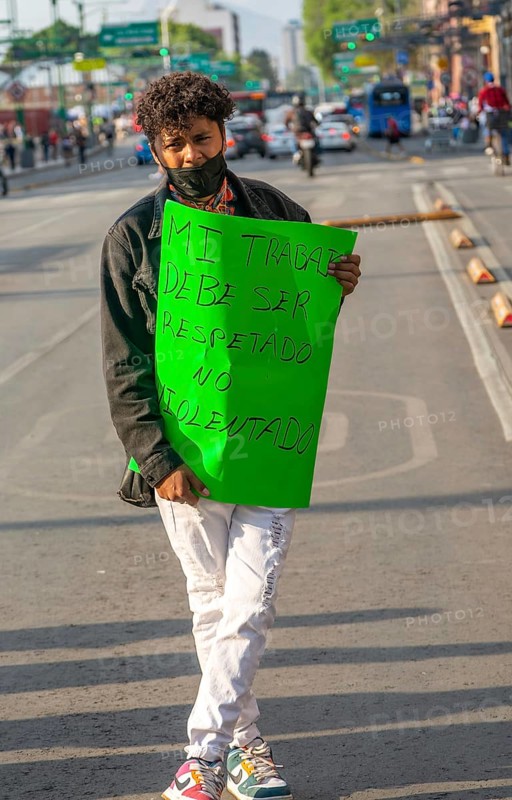 Protestor holding placard blocks traffic on busy city centre road