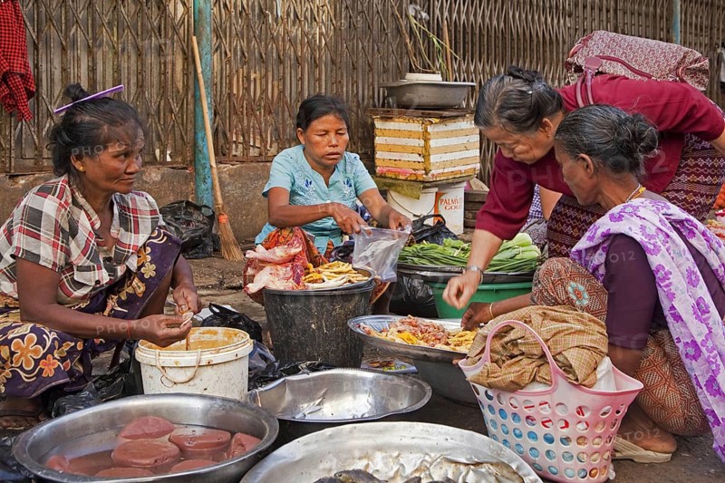 Burmese women selling food on the ground at market in Yangon