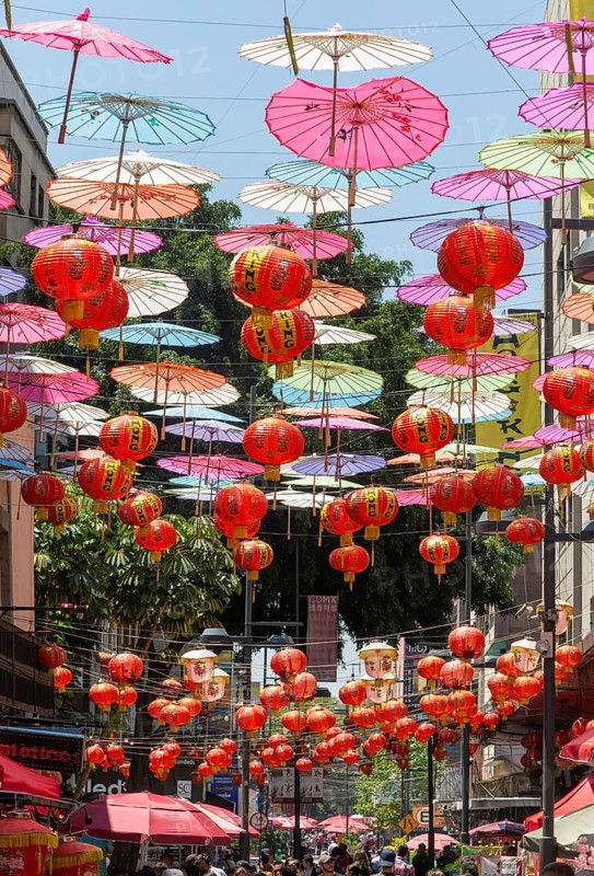 Red paper Chinese lanterns and umbrellas hanging above the street in Chinatown