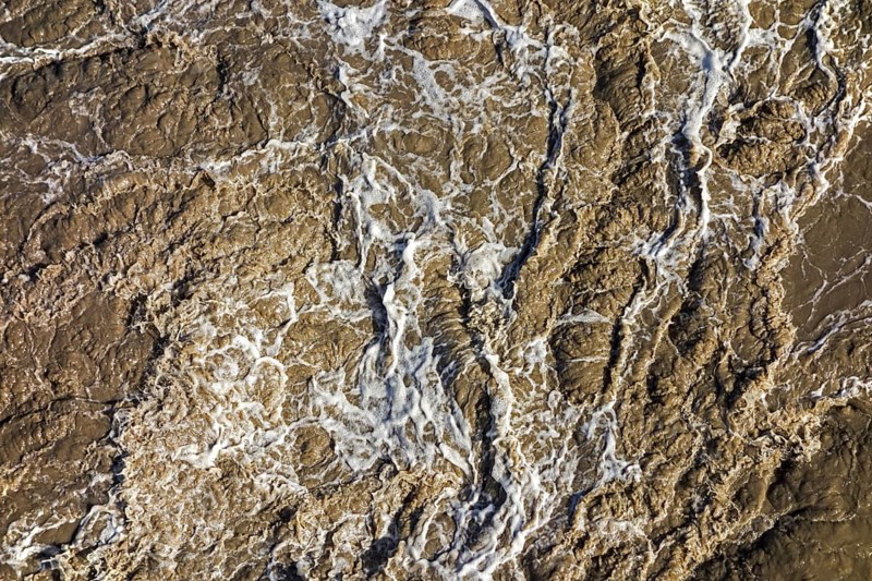 Turbulent muddy sea water caused by ship's screw causing turmoil in wake of boat