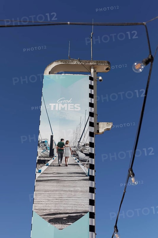 Advertising pillar Good Times with image of a holidaymaker couple
