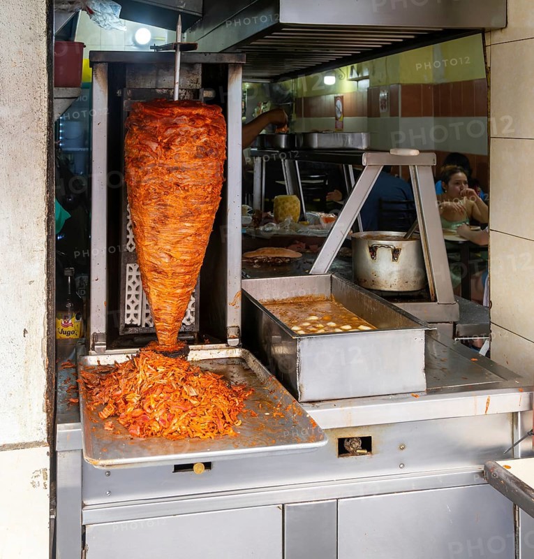Meat grilling on vertical kebab spit in fast food street restaurant