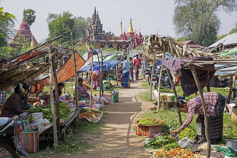 Burmese women selling vegetables at food market in front of Buddhist temples in Myanmar