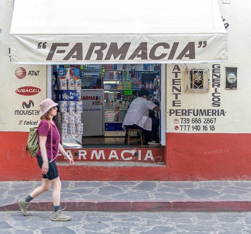 Woman walking past small pharmacy shop