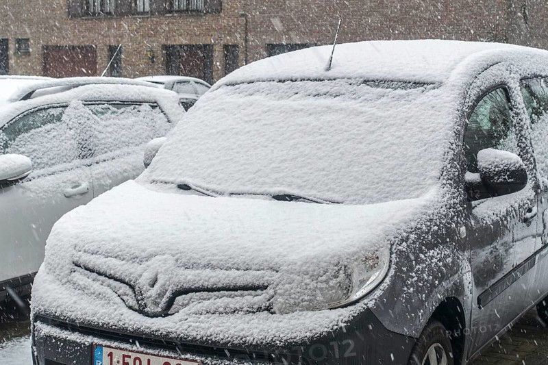 Parked cars covered in snow during unexpected late snow shower in March 2023