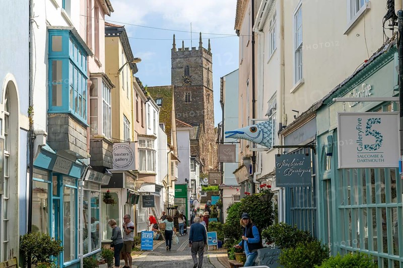 Shops in historic buildings along alleyway with tower of church of St Saviour