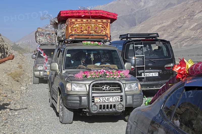 Decorated vehicles loaded with presents on their way to a traditional wedding on the Pamir Highway