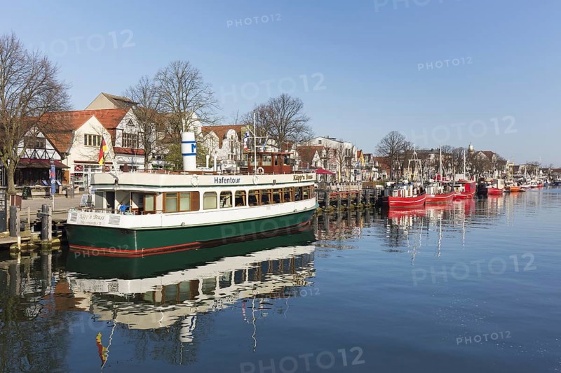 Sightseeing boat and traditional fishing boats in the canal der Alte Strom at Warnemuende in the city Rostock at dusk