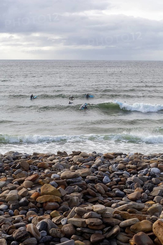 Stones on the beach as surfers ride the waves along the Wild Atlantic way. Strandhill