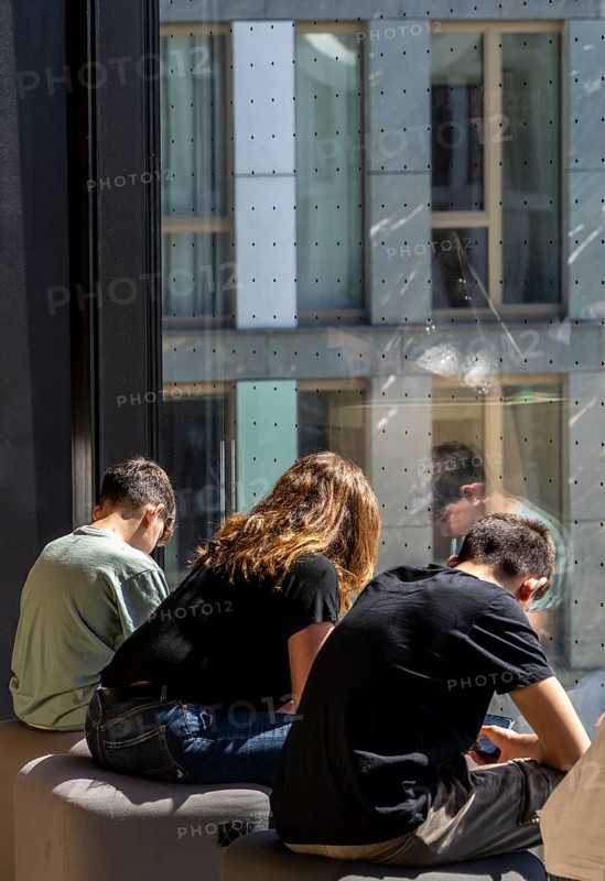 Museum visitors sitting at the window of the Futurium using their smartphones
